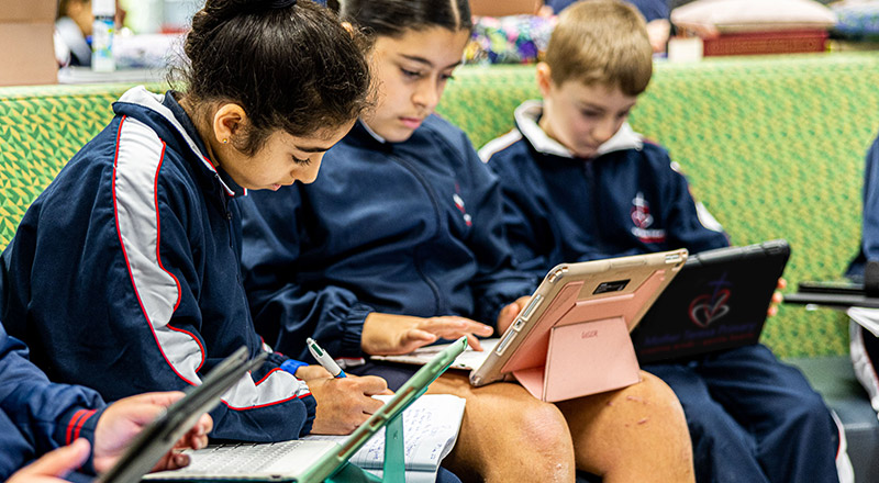 Students sitting on green lounge at Mother Teresa Catholic Primary School Westmead